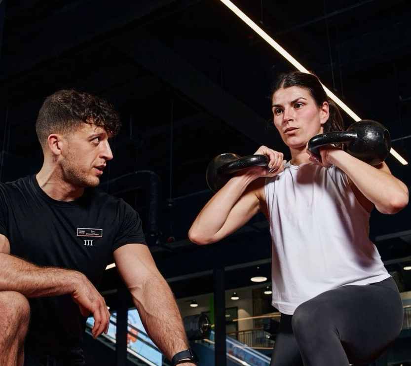 Trainer instructing a woman on kettlebell exercises